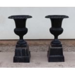 A pair of cast iron black painted campana form garden urns,