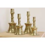 A graduated set of four bell-shaped brass candlesticks,