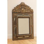 An ebonised and embossed brass wall mirror,