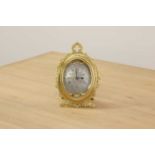An oval brass strut clock,