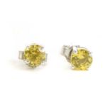A pair of white gold single stone yellow sapphire stud earrings,
