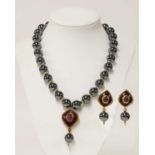 An 18ct gold haematite, ruby and enamel necklace and earrings suite, by Amr Shaker, Geneve, c.1990,