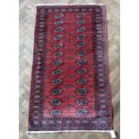 A red ground Pakistan rug with 'Gul' pattern (151cm x 84cm)