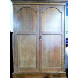 An early 20th century oak cupboard/wardrobe of small proportions; two panelled doors and with plinth