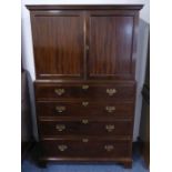 An early 20th century mahogany cupboard-on-chest; the dentil cornice above two panelled doors and an