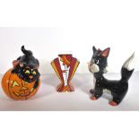 Two Lorna Bailey signed porcelain models of stylised cats, one astride a pumpkin, together with a