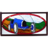 A large multi-coloured stained-glass wallhanging depicting a blue 1920s/30s Bugatti-style racing