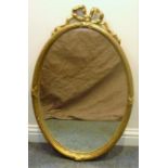 A Classical style, oval, gilt-framed, wall-hanging looking glass surrounded with a ribbon (frame