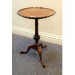 An early 20th century mahogany occasional table; scallop-edged top, turned stem and tripod base (