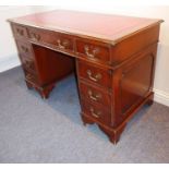 A reproduction mahogany Georgian-style pedestal desk; red-leather-inset top above an arrangement