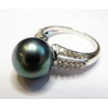 An 18-carat white-gold, grey/black cultured pearl and diamond ring  (The cost of UK postage via