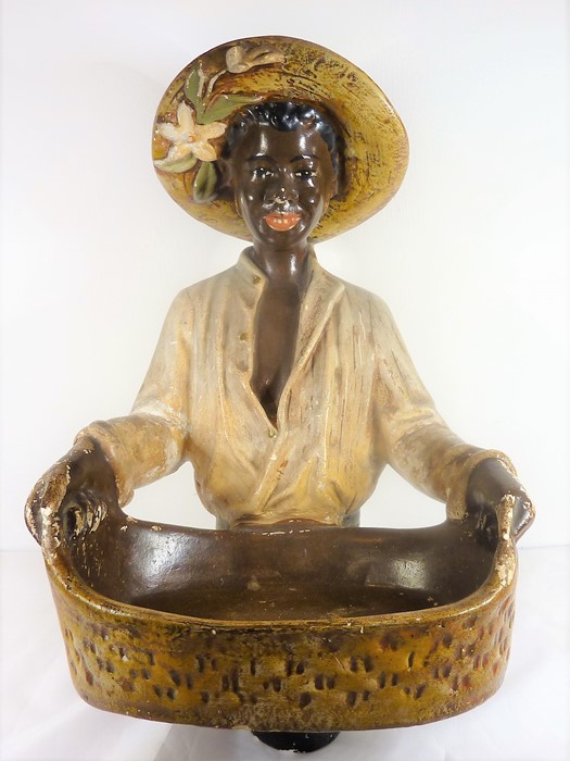 A mid-20th century painted plaster blackamoor-style figure; the smiling figure holds a two-handled