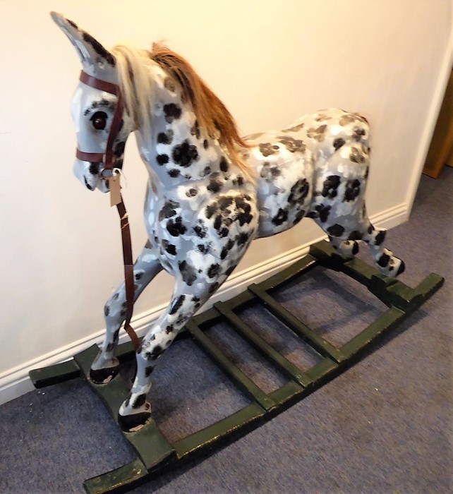 A hand-carved and painted dapple-grey rocking horse with leather bridle and horsehair mane (