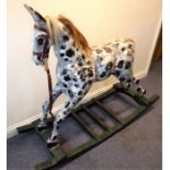 A hand-carved and painted dapple-grey rocking horse with leather bridle and horsehair mane (