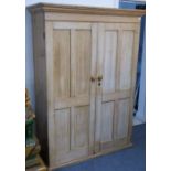 An antique stripped pine wardrobe with two panelled doors and on plinth-style base