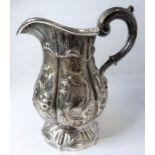 A heavy hallmarked silver baluster-shaped cream jug; later repoussé decorated with flower heads