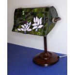 An adjustable 19th century-style (modern) desk lamp; shaped Tiffany-style shade decorated with a