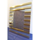 A very stylish modern designer wall-hanging mirror; horizontal gold-coloured batons as 'frame'