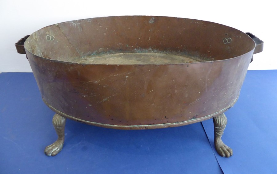 A large late 19th century oval two-handled copper planter; raised on four cast-brass paw-style