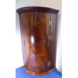 A good early 20th century bow-fronted hanging corner cupboard; of good colour and small proportions,