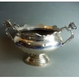 A large hallmarked silver pedestal bowl; two griffin-style trefoil handles affixing to the scalloped