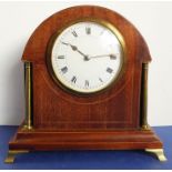 An Edwardian domed mahogany-cased timepiece in good working order; with gilt pillars, white dial