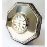 A small octagonal silver framed desk clock; white enamel dial with Roman numerals and signed 'Kitney