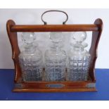 A late 19th / early 20th century three-decanter tantalus: the cut-glass decanters with some damage