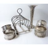 A small silver group to include four various silver napkin rings, a small trumpet-shaped bud vase (