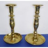 A pair of very heavy cast-brass candlesticks with large circular drip-pans as bases (23cm high)