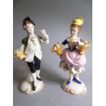 A pair of Continental hand-decorated porcelain figure models: a young boy in green tunic holding a