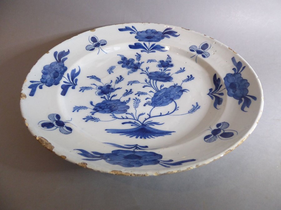 A large 18th century circular tin-glazed earthenware dish; hand painted in blue and white