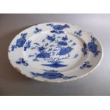 A large 18th century circular tin-glazed earthenware dish; hand painted in blue and white