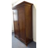 An 18th century-style (early) two-door mahogany wardrobe; dentil cornice above panelled doors and