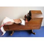 A antique pine cot with pillows and bedding and including dolls and a teddy bear
