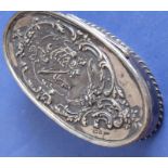 An oval hallmarked silver box with hinged lid; the lid decorated repoussé style with a lady in a