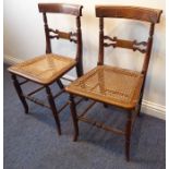 A pair of late Regency grained bedroom chairs having brass-inlaid crest rails and rattan-caned