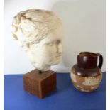 An ancient-style (modern) plaster bust of a female head locating upon a stained-hardwood wooden