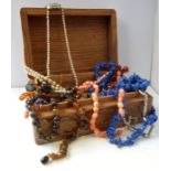 A carved hardwood box containing a variety of jewellery (mostly necklaces); to include lapis lazuli,