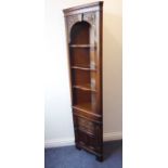 A reproduction oak freestanding corner cupboard of slim proportions; the cornice above two carved