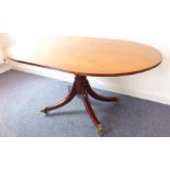 A Regency period oval mahogany tilt-top breakfast table on turned stem with four downswept legs