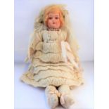 A late 19th/early 20th century doll dressed in cream-coloured knitted tunic
