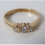 A diamond three-stone ring; the three old brilliant-cut diamonds to the 9-carat yellow-gold plain