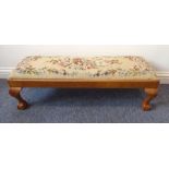 An early 20th century walnut footstool having drop in floral needlework top