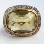 A citrine and diamond-set dress ring, the oval rose-cut citrine collet set above a surround of