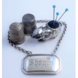 Two silver thimbles, a silver rabbit pincushion and a silver 'Sherry' decanter label (The cost of UK