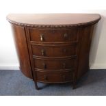 An early 20th century demi-lune mahogany side cabinet; the gadrooned top above an arrangement of