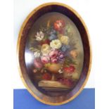 E M BALL; a fine oval oil on panel still-life study of flowers in a vase upon a plinth base;