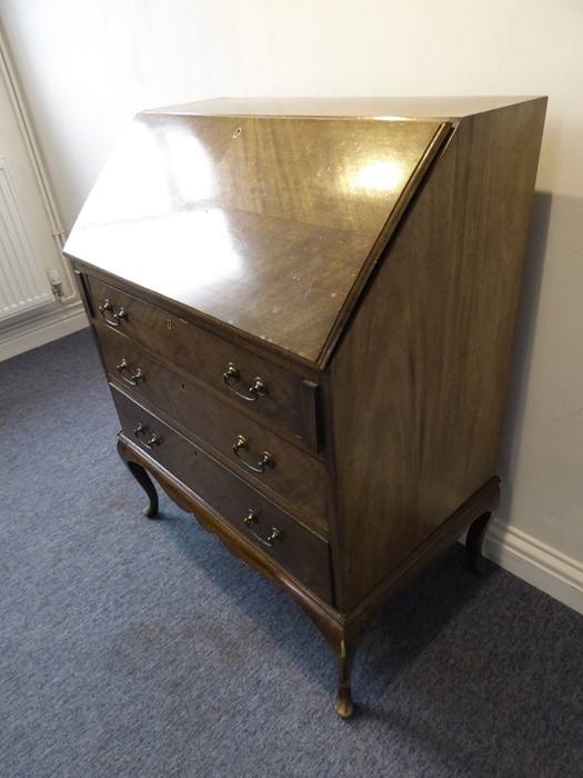 An early 20th century walnut writing bureau; the quarter-veneered sloping fall opening to reveal