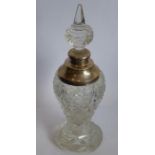 A cut-glass baluster-shaped scent bottle on spreading circular foot; the spire stopper above a